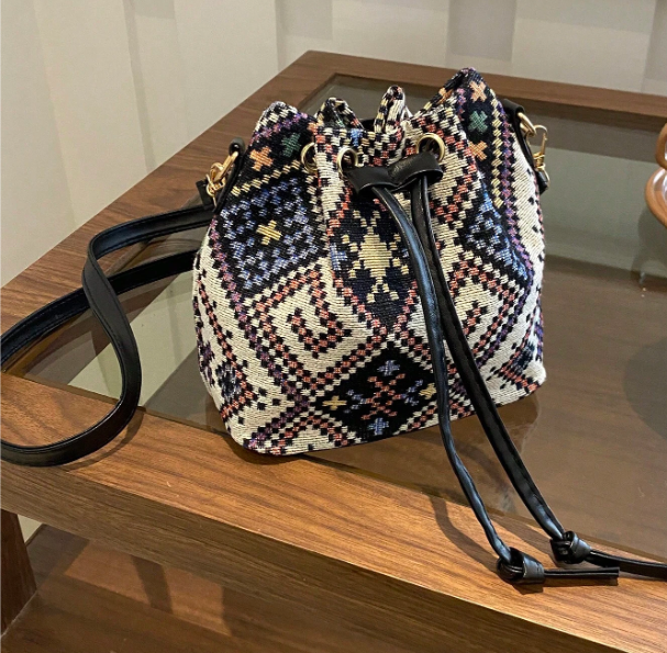 Get ready to brighten up your spring wardrobe with this colorful bucket style shoulder bag! Features include an adjustable strap and handy drawstring closure. This petite bag is fashionable and functional- able to hold your phone, wallet & keys.