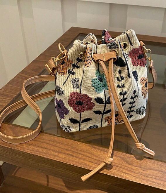 Get ready to brighten up your spring wardrobe with this colorful bucket style shoulder bag! Features include an adjustable strap and handy drawstring closure. This petite bag is fashionable and functional- able to hold your phone, wallet & keys.