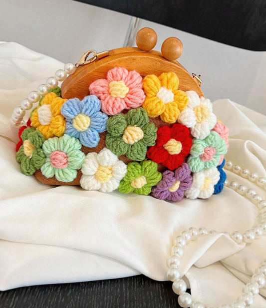 EVERY little girl needs this daintly little purse fit for all the princesses out there! The whimsical design includes yarn flowers in bright colors and a unique pearl string strap, this bag adds a touch of charm to any outfit.