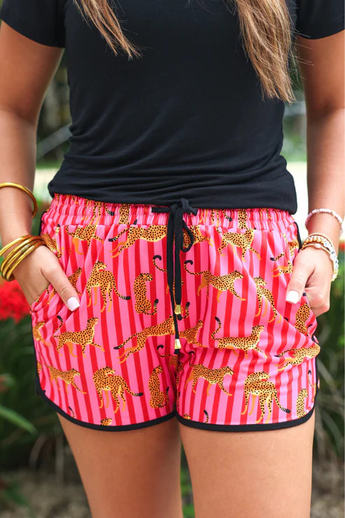 Person wearing a black top and pink shorts with gold animal patterns.