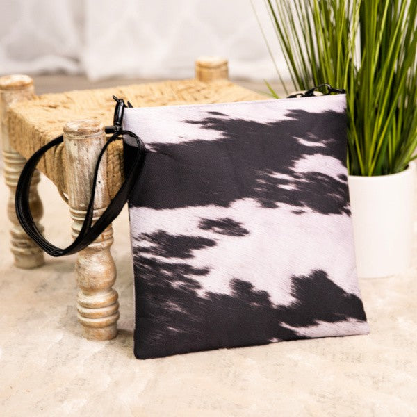 Vegan Leather / Cotton  This cow print tote is "Mootiful"! The strap is adjustable and the tote is generous but slim and features both a top zip as well as a back zipped pocket- stand out in the herd with this one!  Size: 11.5" x 12"