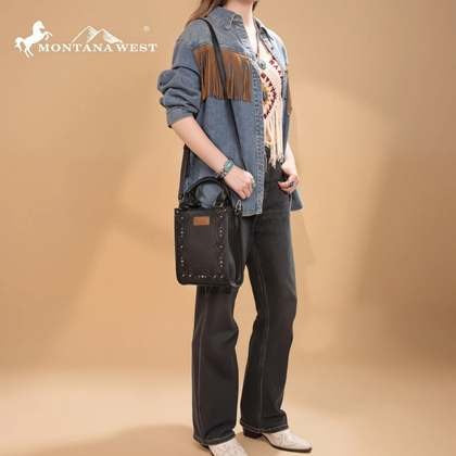 Person wearing a denim shirt and black pants holding a black bag with Montana West logo.