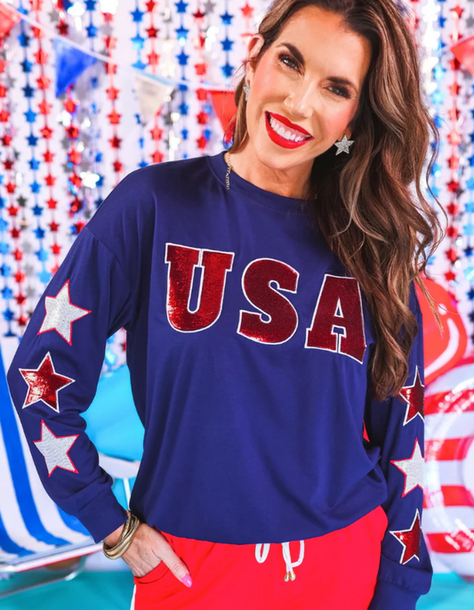 60% polyester / 35% rayon / 5% spandex

Get ready to shine with our USA Sequin Star Top! Featuring eye-catching sequin lettering and star sleeves outline in embroidery, this top is perfect for making a statement. Order yours now and be the star of any event!

Suggested Sizing: Small fits size 2-4; Medium fits size 6-8; Large fits size 10-12; XL fits 14-16; 2XL fits 18