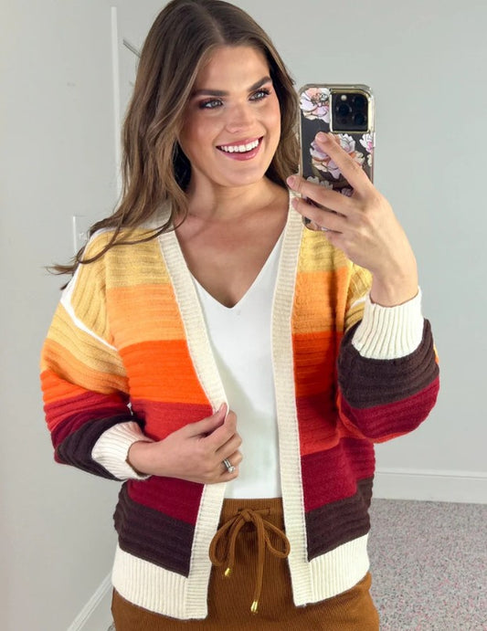 Woman taking a mirror selfie wearing a colorful striped cardigan.