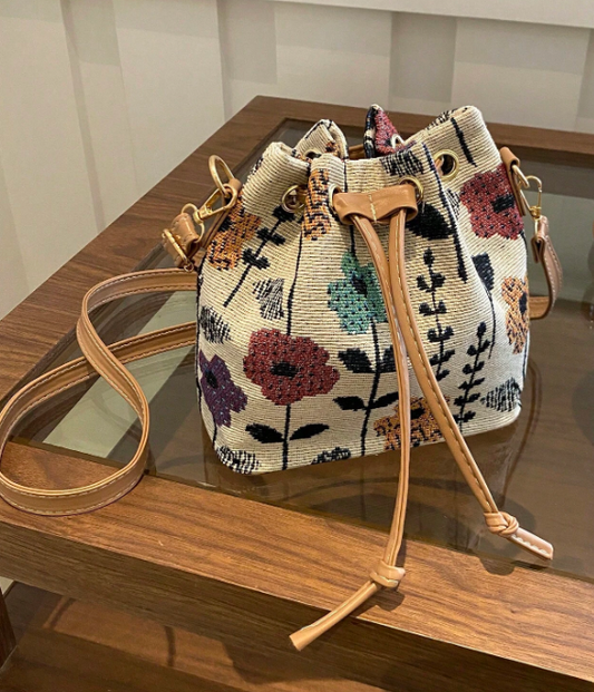 Get ready to brighten up your spring wardrobe with this colorful bucket style shoulder bag! Features include an adjustable strap and handy drawstring closure. This petite bag is fashionable and functional- able to hold your phone, wallet &amp; keys.