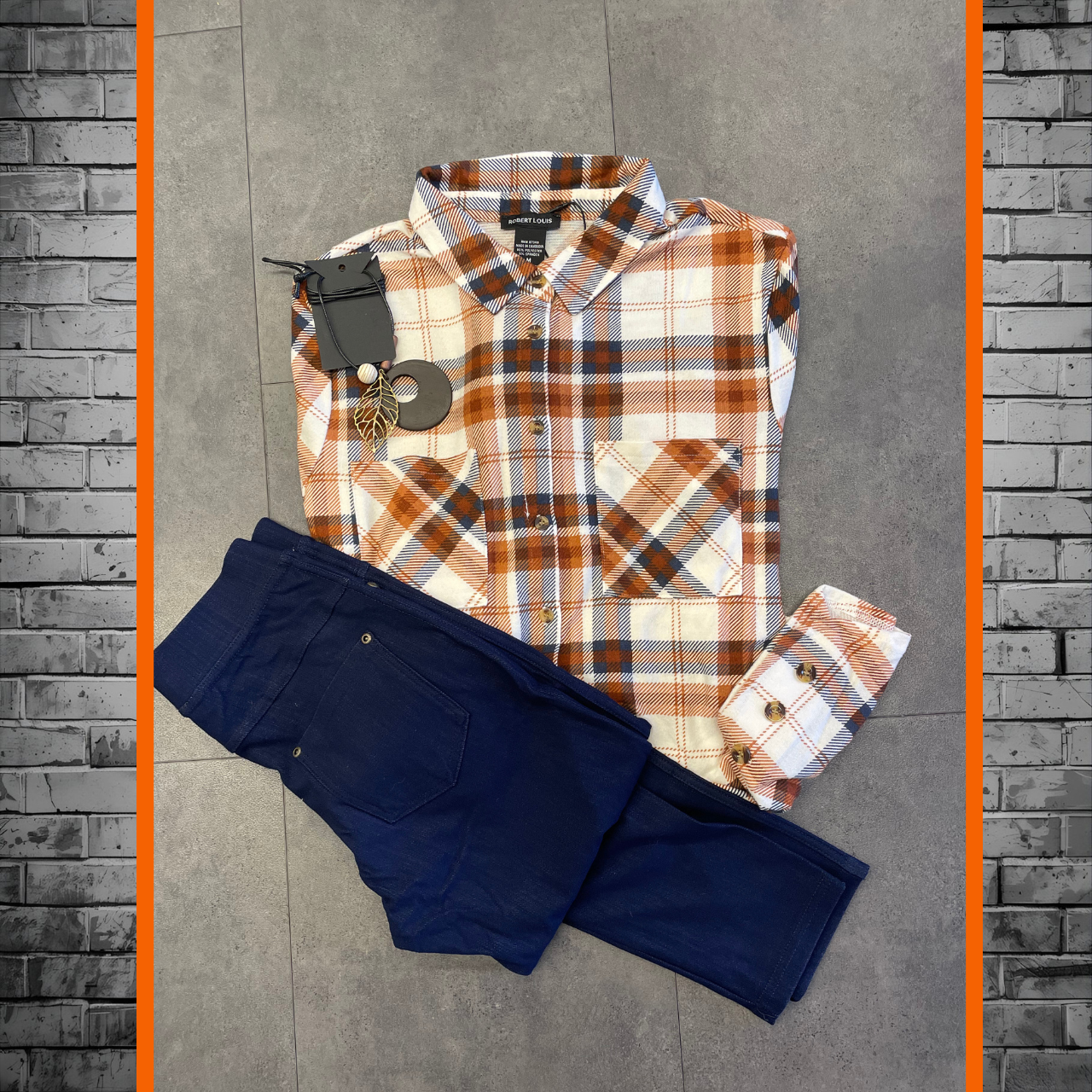 Plaid shirt and navy pants on a gray tiled floor with brick border