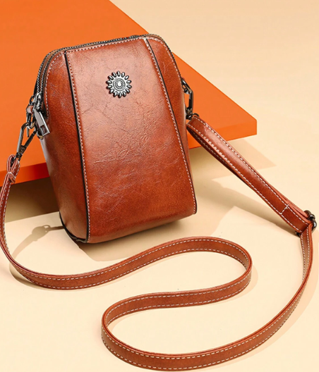 This fun-sized crossbody packs a punch with its ample storage, surpassing even larger minis! The classic brown faux leather adds some serious style - a perfect pick every time!