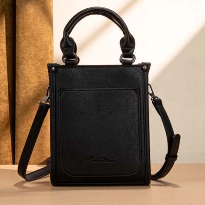 Black handbag with a strap on a neutral background